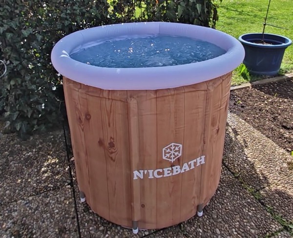 RefreshPod in Holz-Optik auf Gartenplatten vor einer Hecke